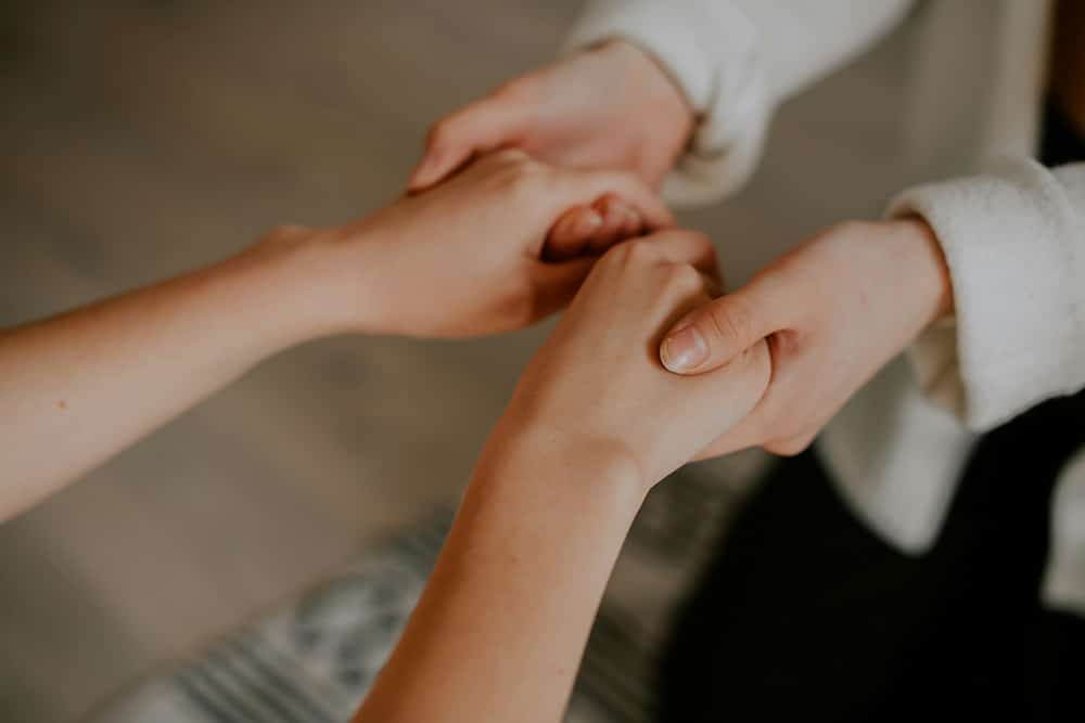 A woman reaches her hands out for support from a friend, an important part of successfully navigating change in recovery.