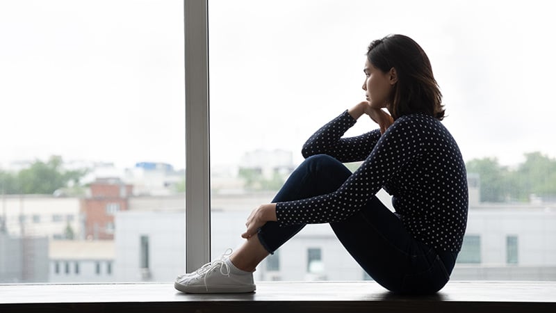 A woman struggling with a mental health disorder looks out the window.