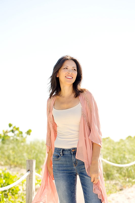 A woman stands outside in nature.