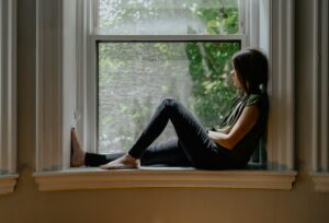 woman sitting by window trauma and addiction in women